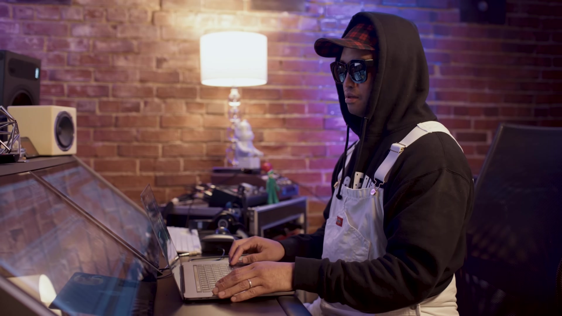 Chad Hugo in sunglasses and white overalls, working at a studio console